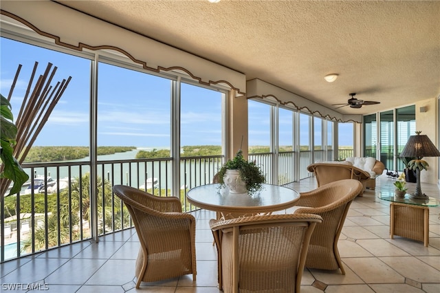 sunroom featuring a water view and ceiling fan