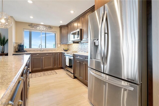 kitchen with recessed lighting, a sink, appliances with stainless steel finishes, backsplash, and decorative light fixtures