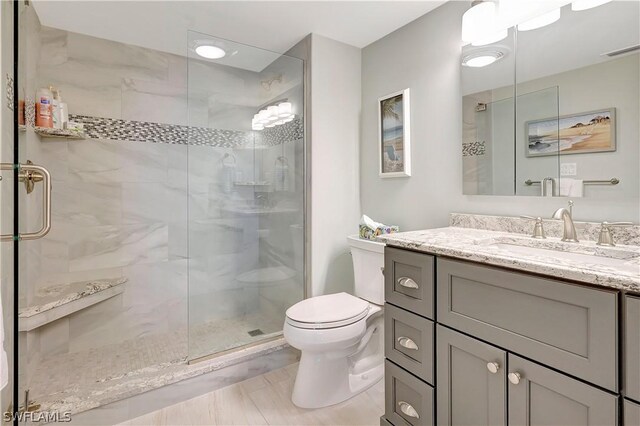 full bathroom with toilet, a stall shower, visible vents, and vanity