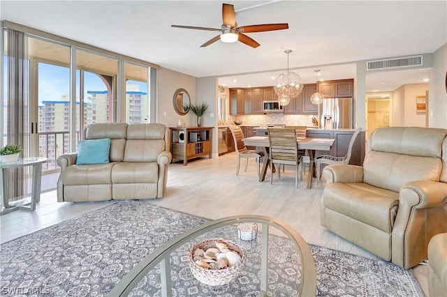 living area with ceiling fan with notable chandelier, floor to ceiling windows, a city view, light wood-style flooring, and visible vents