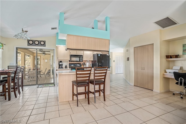 kitchen featuring a breakfast bar area, black appliances, and light tile floors