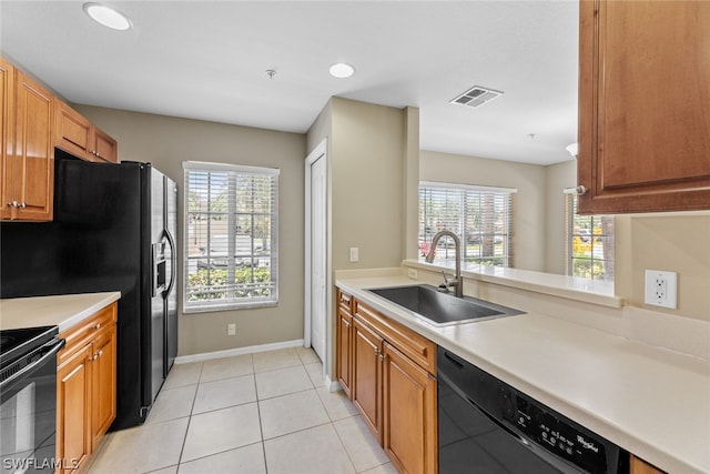 kitchen with black appliances, a wealth of natural light, sink, and light tile flooring