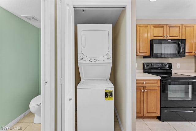 clothes washing area with stacked washing maching and dryer and light tile patterned floors