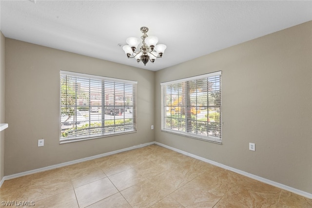 spare room with a notable chandelier and light tile patterned flooring