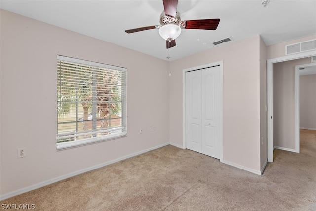 unfurnished bedroom with light carpet, a closet, and ceiling fan