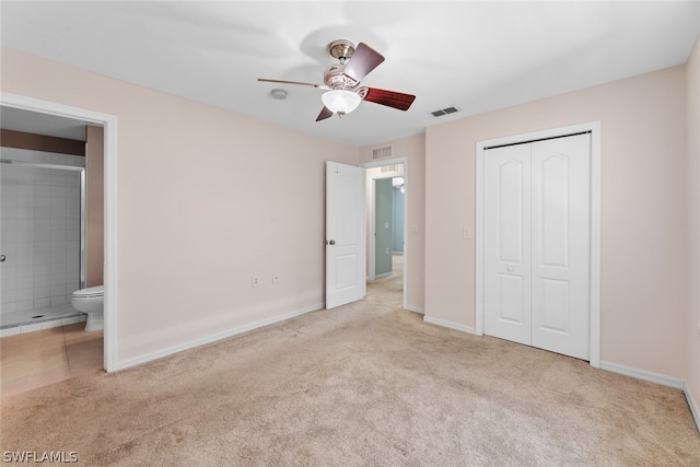 unfurnished bedroom featuring light carpet, connected bathroom, a closet, and ceiling fan