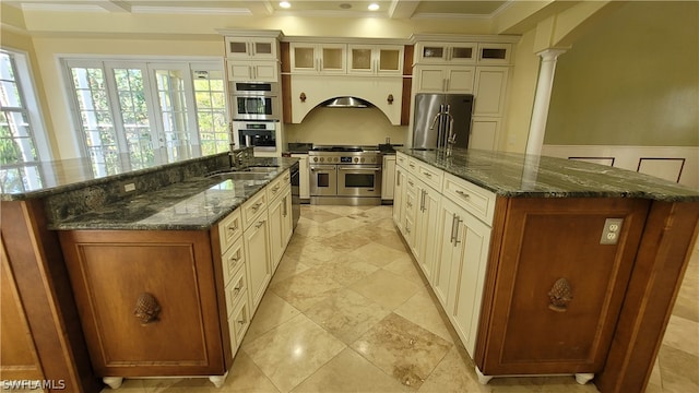 kitchen with premium appliances, ornate columns, a large island, and dark stone counters