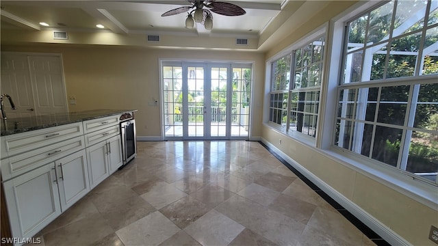 kitchen featuring dark stone countertops, ceiling fan, a healthy amount of sunlight, and light tile patterned floors