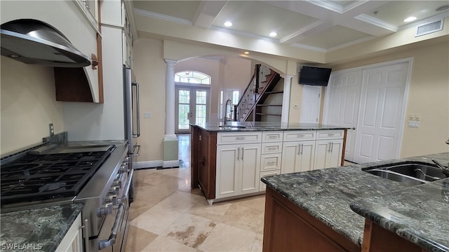 kitchen featuring white cabinetry, dark stone countertops, coffered ceiling, double oven range, and a kitchen island with sink