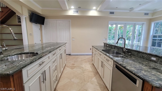 kitchen featuring white cabinetry, dark stone countertops, a center island with sink, and stainless steel dishwasher