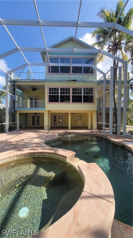 view of swimming pool with glass enclosure, a patio area, and ceiling fan