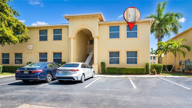 view of building exterior with stairs and uncovered parking