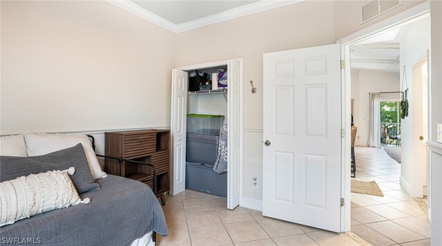 tiled bedroom featuring a closet and crown molding