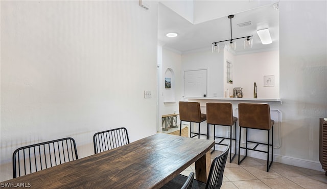 tiled dining area featuring crown molding and rail lighting