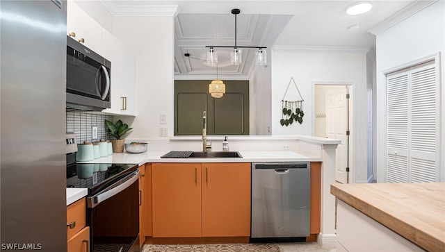 kitchen with appliances with stainless steel finishes, white cabinets, pendant lighting, and sink