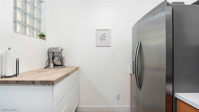 kitchen with butcher block countertops, white cabinets, and stainless steel fridge with ice dispenser