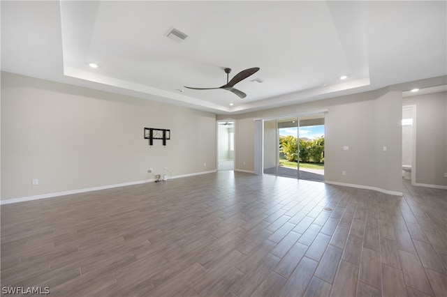 empty room with ceiling fan, a raised ceiling, and wood-type flooring