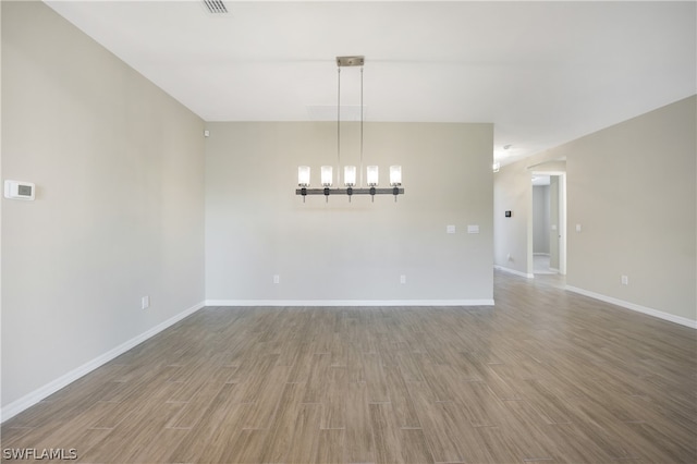 empty room featuring a notable chandelier and hardwood / wood-style floors