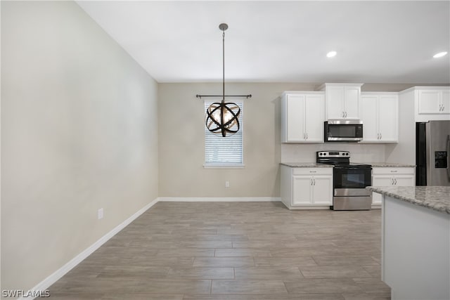 kitchen featuring hanging light fixtures, light stone countertops, stainless steel appliances, white cabinets, and backsplash