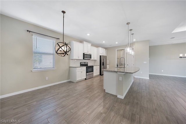 kitchen featuring hardwood / wood-style floors, pendant lighting, sink, white cabinetry, and appliances with stainless steel finishes