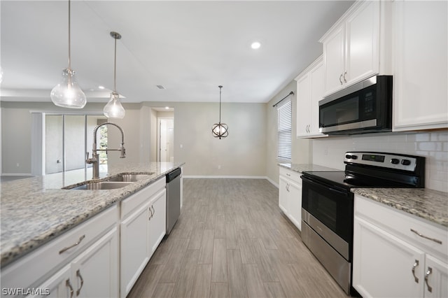 kitchen with light stone countertops, tasteful backsplash, stainless steel appliances, hanging light fixtures, and white cabinetry