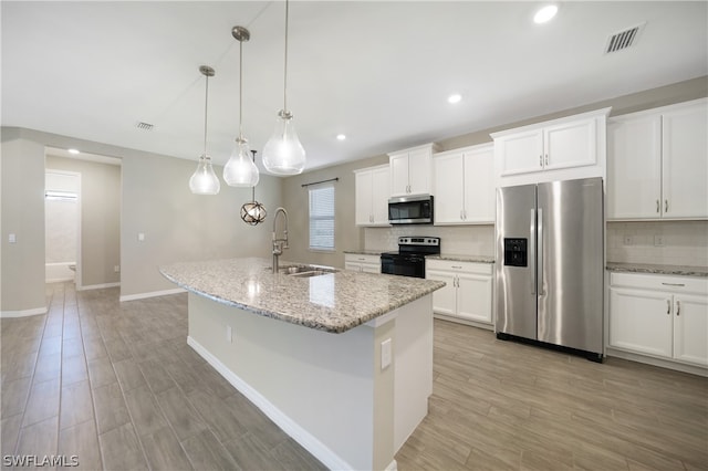 kitchen featuring stainless steel appliances, tasteful backsplash, a kitchen island with sink, white cabinets, and pendant lighting