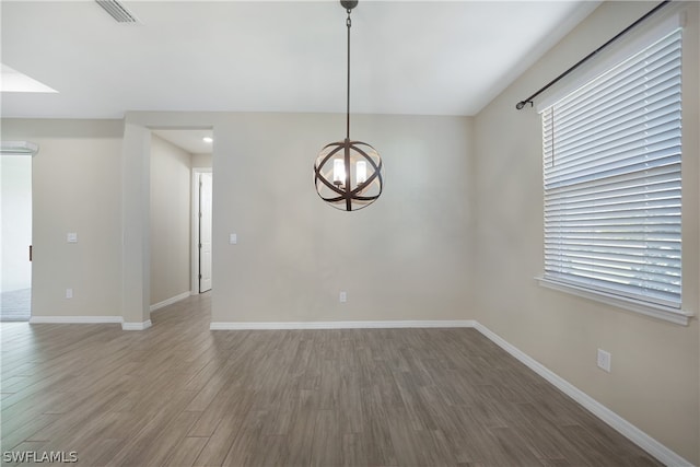 spare room featuring wood-type flooring and an inviting chandelier