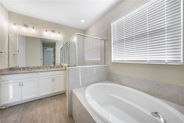 bathroom with double vanity, hardwood / wood-style flooring, and plus walk in shower