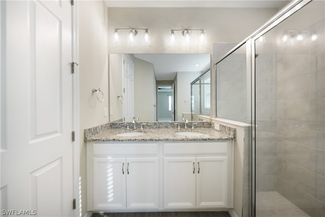 bathroom with dual bowl vanity and an enclosed shower