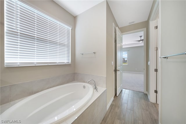 bathroom featuring ceiling fan and tiled tub