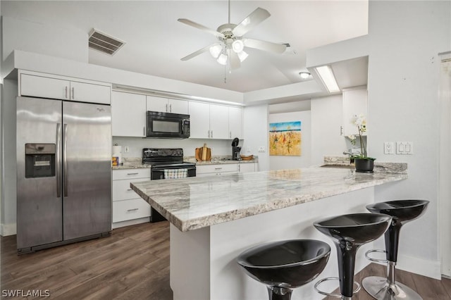 kitchen with black appliances, white cabinets, kitchen peninsula, and a kitchen breakfast bar