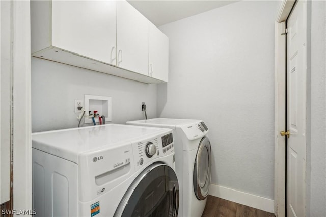 washroom featuring dark wood-type flooring, washer and dryer, and cabinets