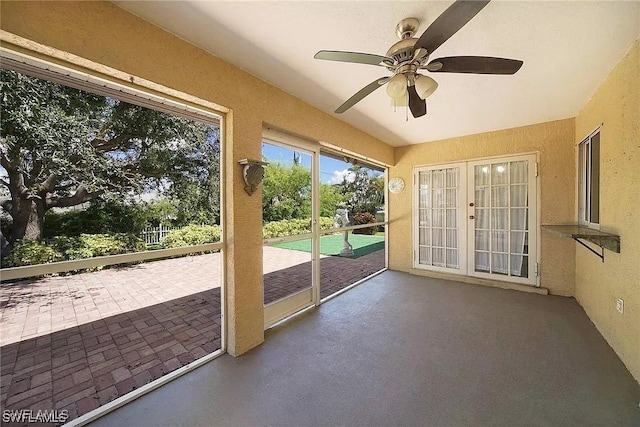 unfurnished sunroom featuring ceiling fan and french doors