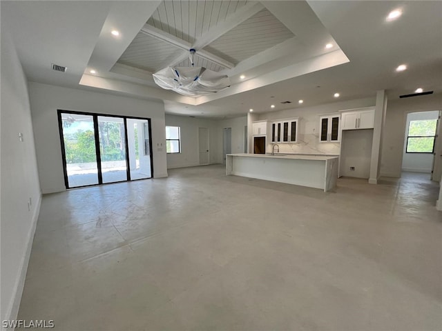 unfurnished living room featuring a raised ceiling, a wealth of natural light, and sink