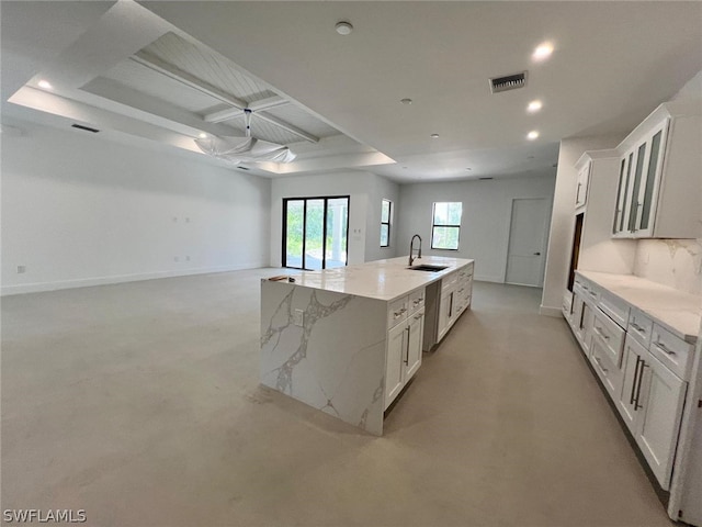 kitchen featuring a large island, light stone countertops, white cabinetry, and sink