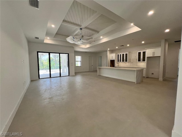 unfurnished living room featuring a tray ceiling and sink