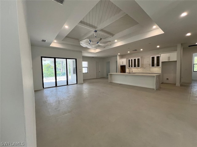 unfurnished living room featuring a raised ceiling and sink