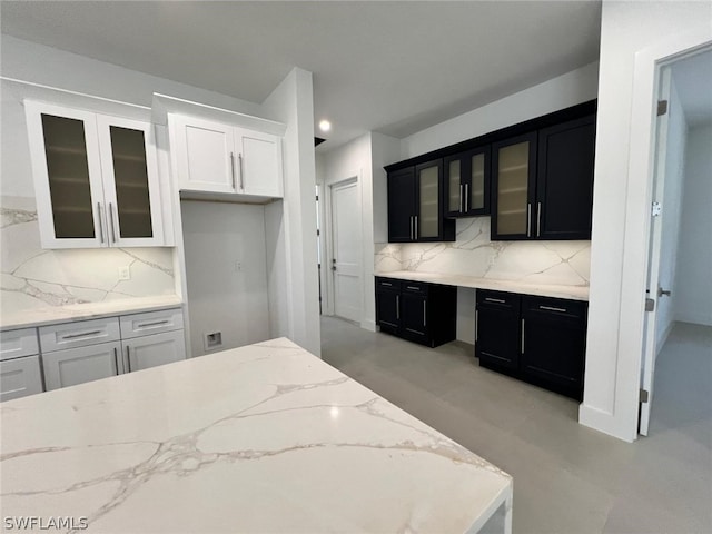 kitchen with decorative backsplash, light stone countertops, and white cabinetry