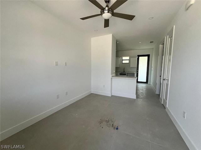 unfurnished living room with ceiling fan and concrete flooring