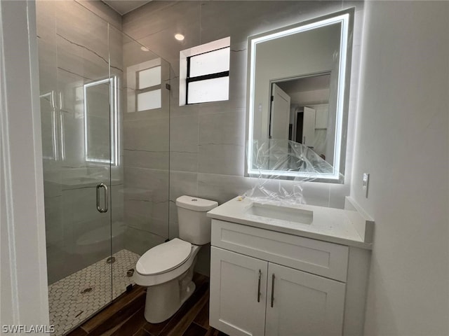 bathroom featuring toilet, vanity, tile walls, and walk in shower