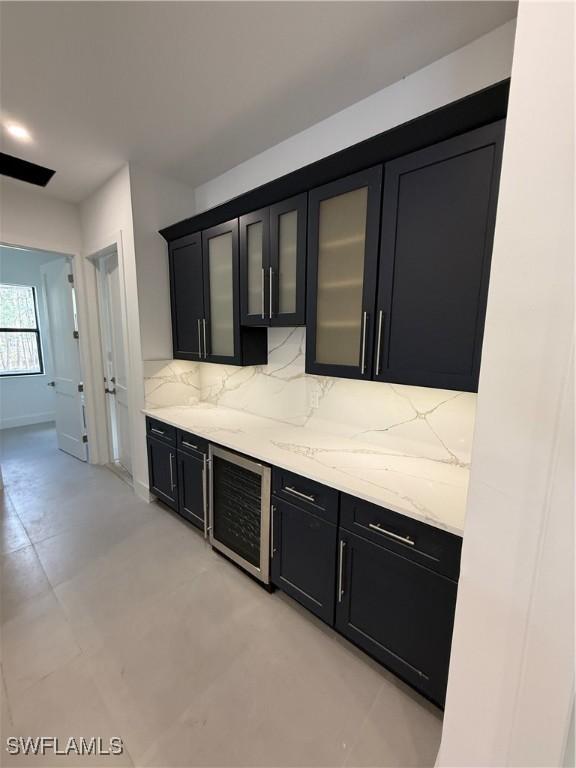 bar featuring light stone countertops, beverage cooler, and decorative backsplash