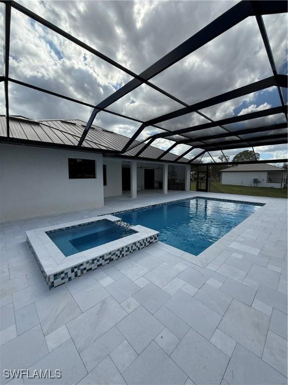 view of swimming pool with an in ground hot tub, a patio, and glass enclosure