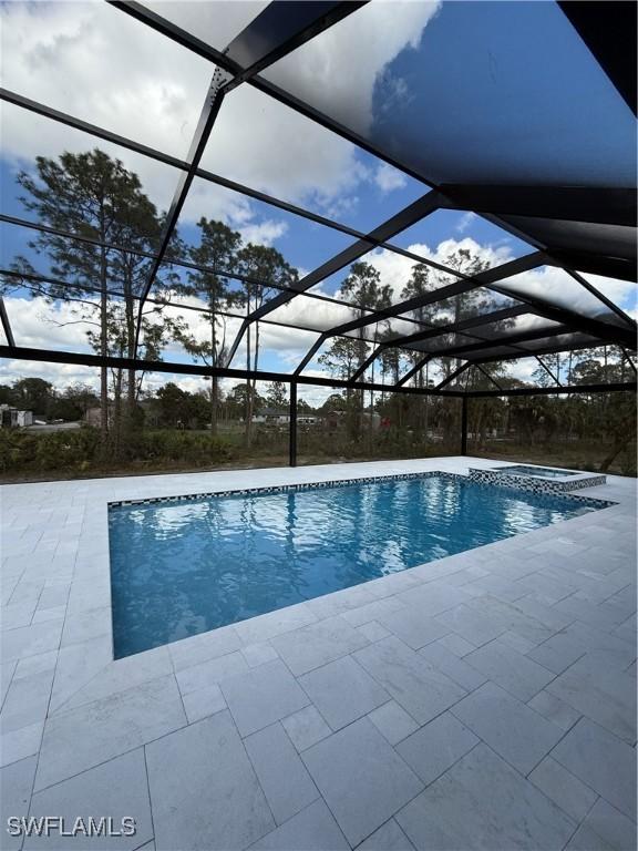 view of swimming pool featuring a hot tub, a lanai, and a patio area