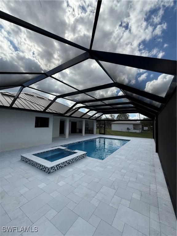 view of pool with a patio area, glass enclosure, and an in ground hot tub