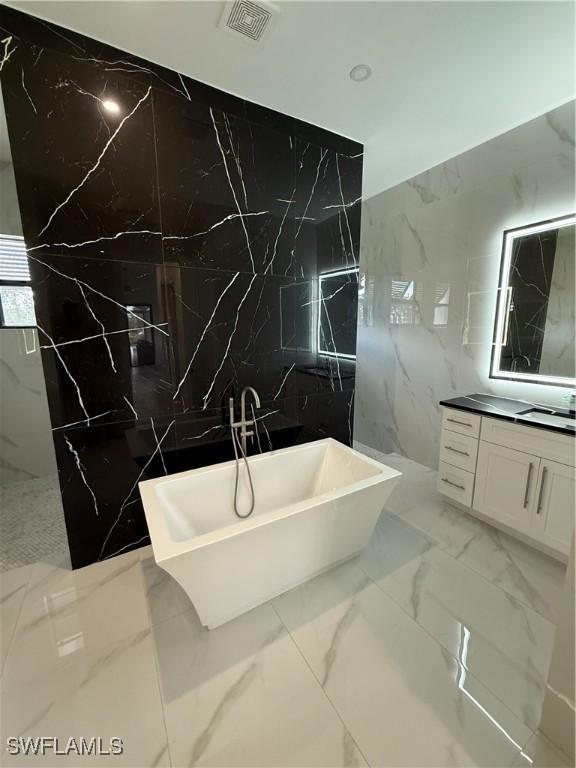 bathroom with a washtub, vanity, and tile walls