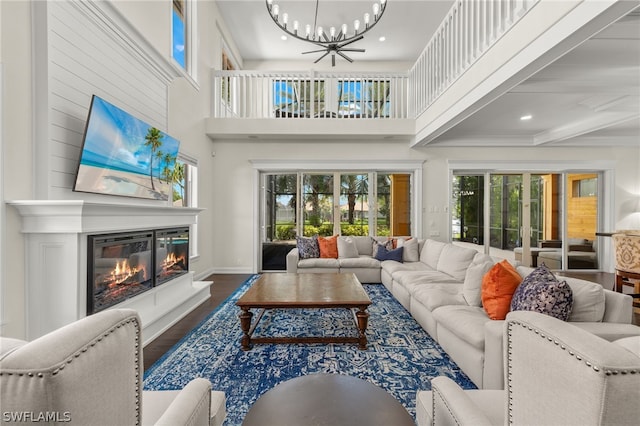 living room with a towering ceiling, a chandelier, and hardwood / wood-style flooring