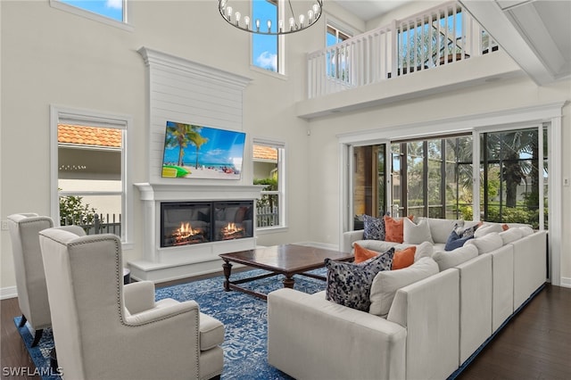 living room with a high ceiling, a notable chandelier, and dark hardwood / wood-style flooring