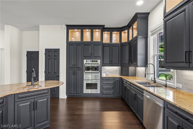 kitchen featuring dark hardwood / wood-style flooring, appliances with stainless steel finishes, sink, and light stone countertops