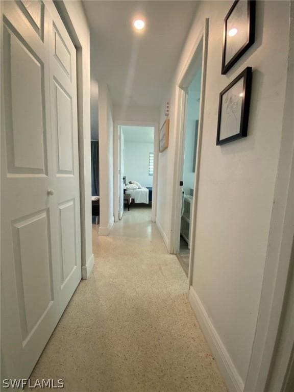 hall featuring light speckled floor, recessed lighting, and baseboards