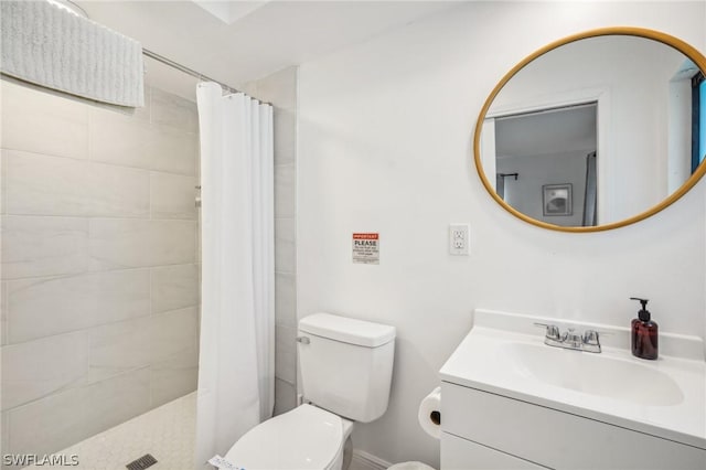 bathroom featuring toilet, tiled shower, and vanity